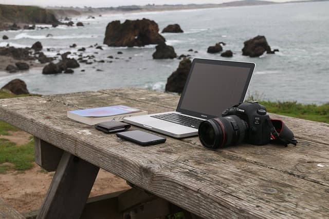 海の近くのベンチの上のパソコンとカメラ